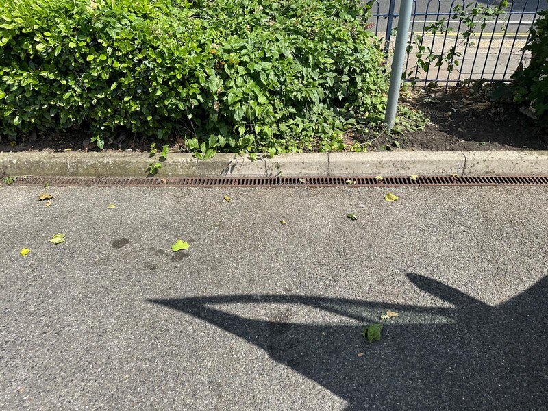Linear trench drain maintenance beside a commercial kerb